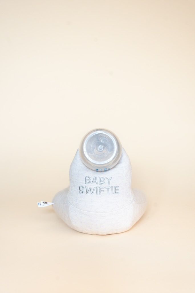 White baby bottle with 'Baby Swiftie' branding on a beige background